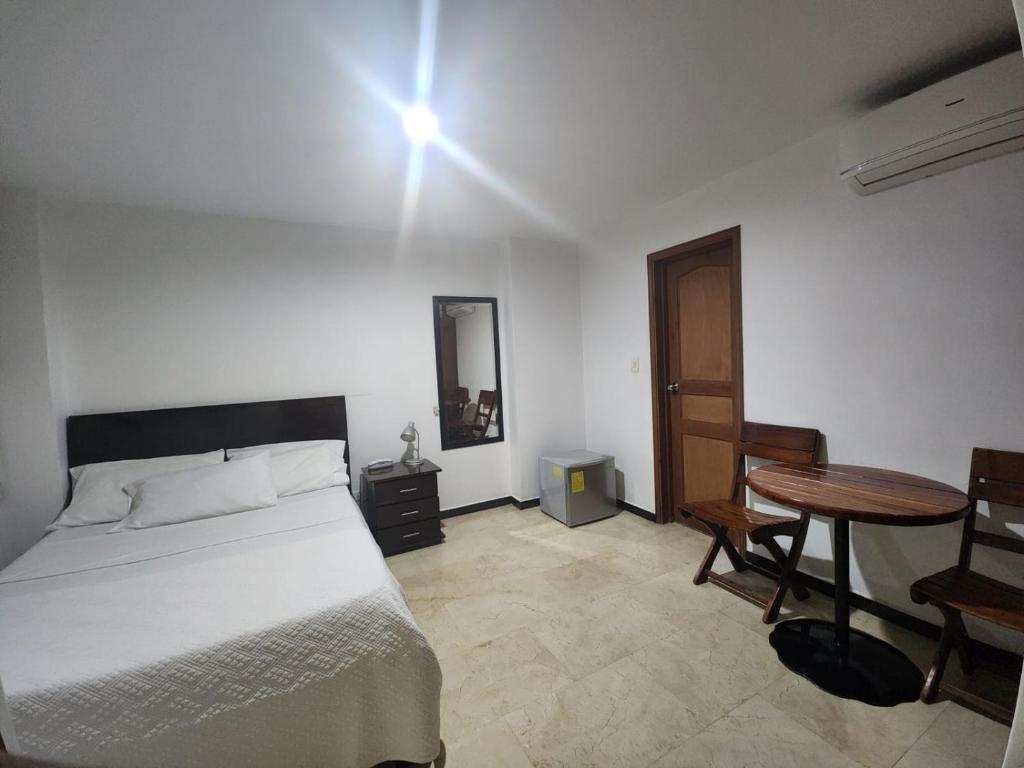 a bedroom with a bed and a table and a mirror at Hotel Ciudad Capri in Cali