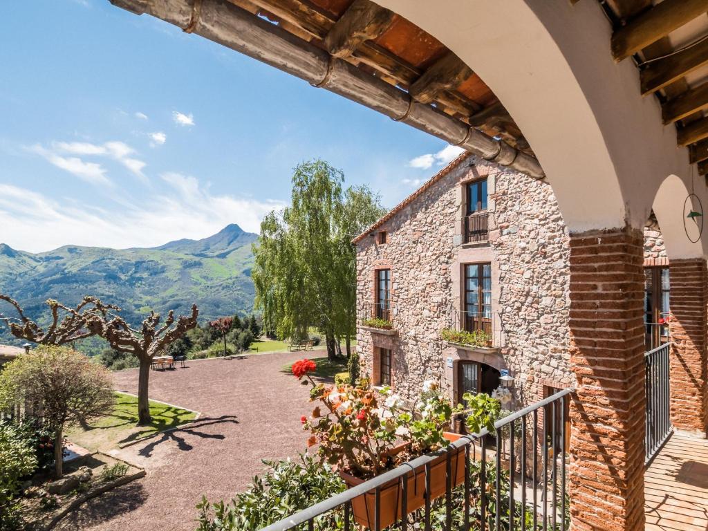 an external view of a house with mountains in the background at Masovería Ca la Maria in Arbúcies