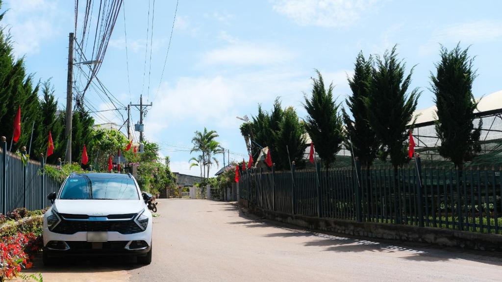 a white car parked on a street next to a fence at Da Quy Harmony Homestay in Da Lat