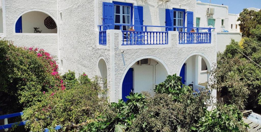 Casa blanca con puertas y árboles azules en Villa Dioni en Kamari