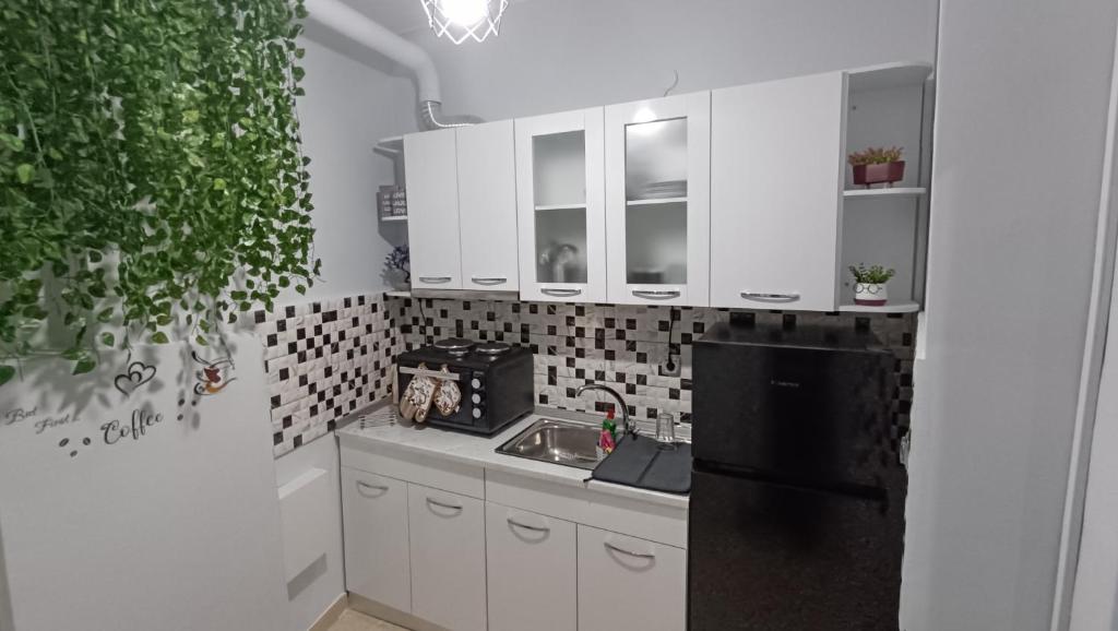 a kitchen with white cabinets and a black refrigerator at M&M's house in Thessaloniki