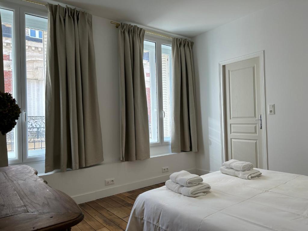 a white room with a bed with towels on it at Les Hortensias in Épernay