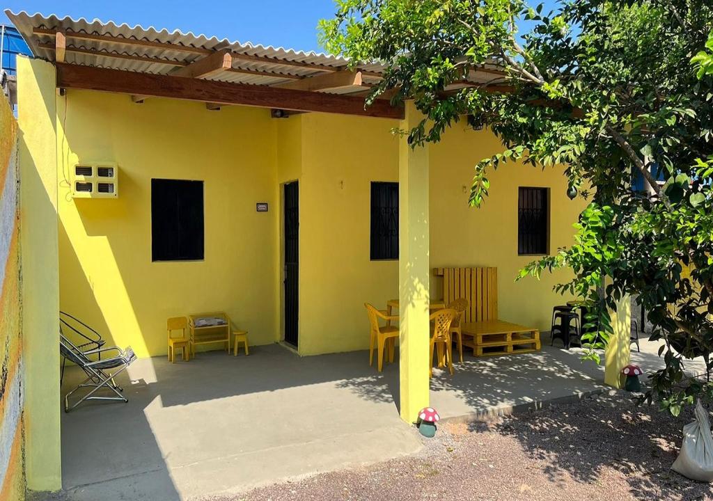 uma casa amarela com um pátio com uma mesa e cadeiras em Casa Amarela em Presidente Figueiredo