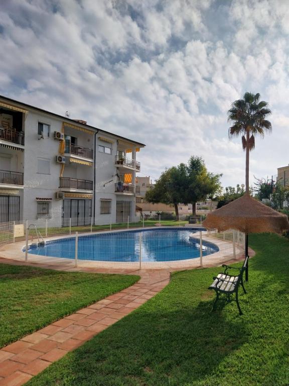 a swimming pool with an umbrella next to a building at Torremolinos Playa Carihuela in Torremolinos