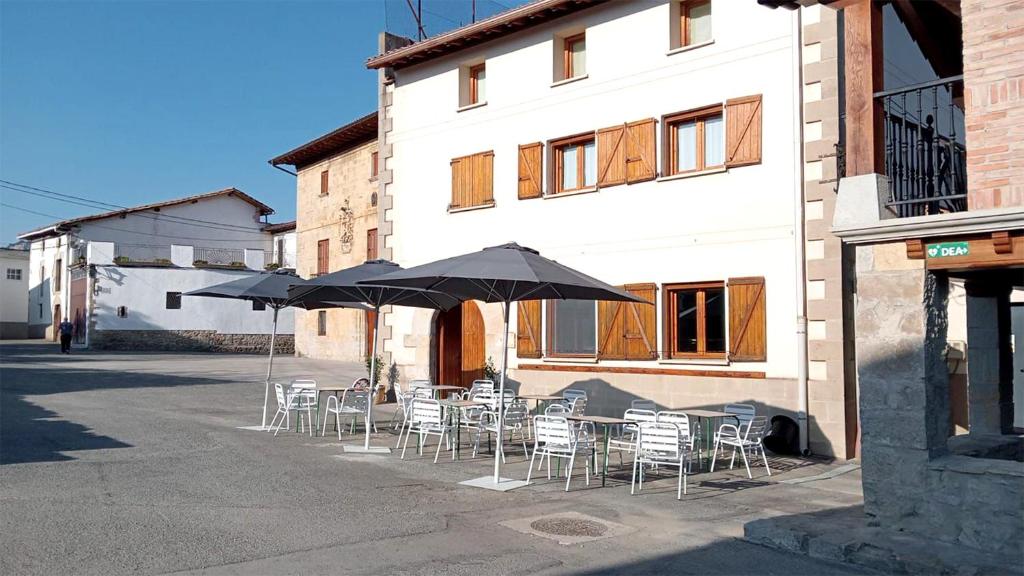 un gruppo di tavoli e sedie con ombrelloni di fronte a un edificio di Posada de Ollo a Ollo