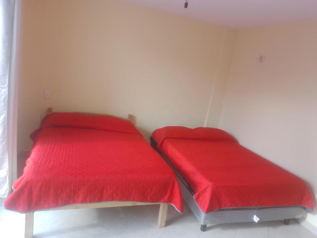 two beds in a room with red sheets at Puerto mar 2 in Acapulco