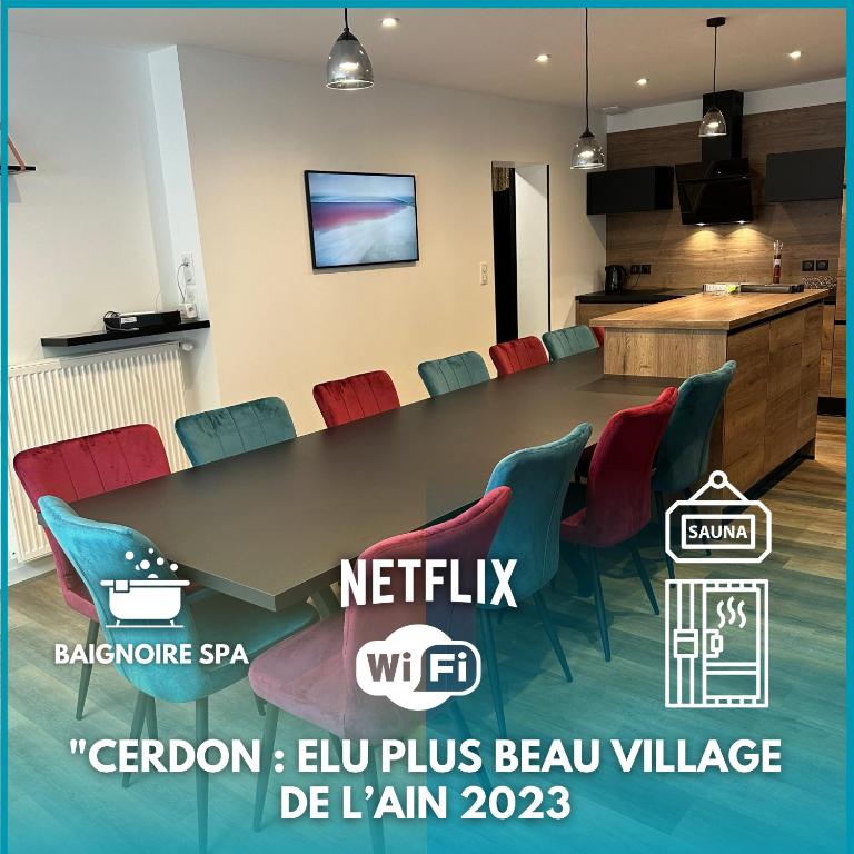 une salle de conférence avec une table et des chaises colorées dans l'établissement La Marionnade - Maison de village, Sauna, Balnéothérapie, Borne VE, à Cerdon