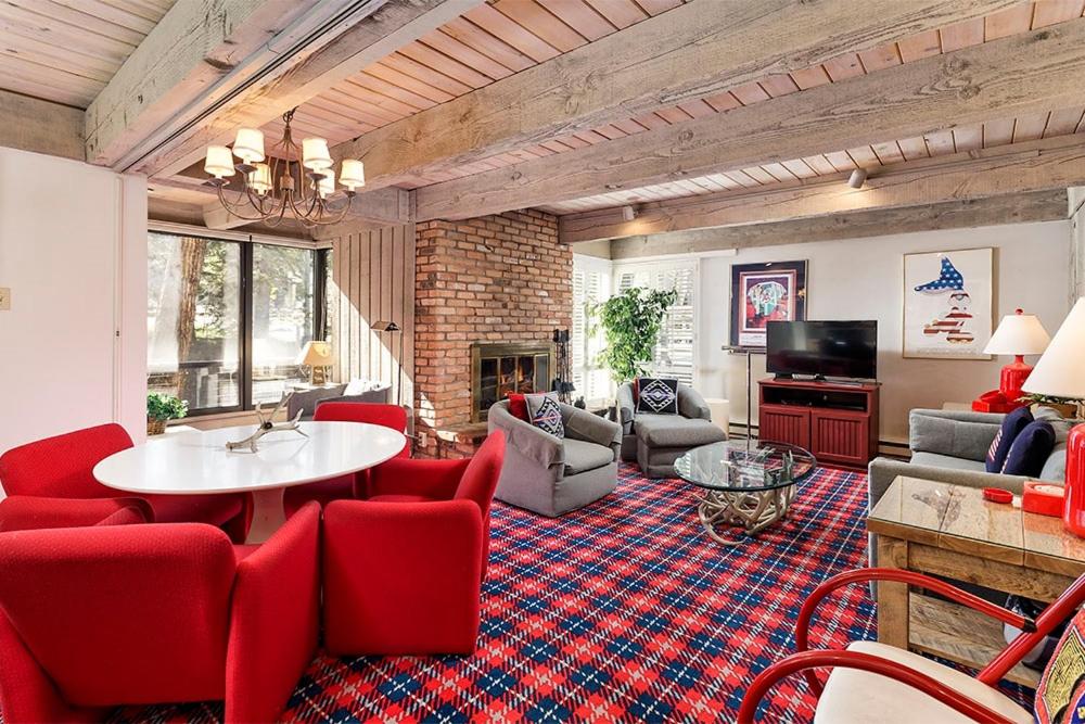 a living room with red chairs and a table at Chateau Eau Claire Unit 1, Stylish Condo Overlooking the River, Walking Distance to Downtown in Aspen
