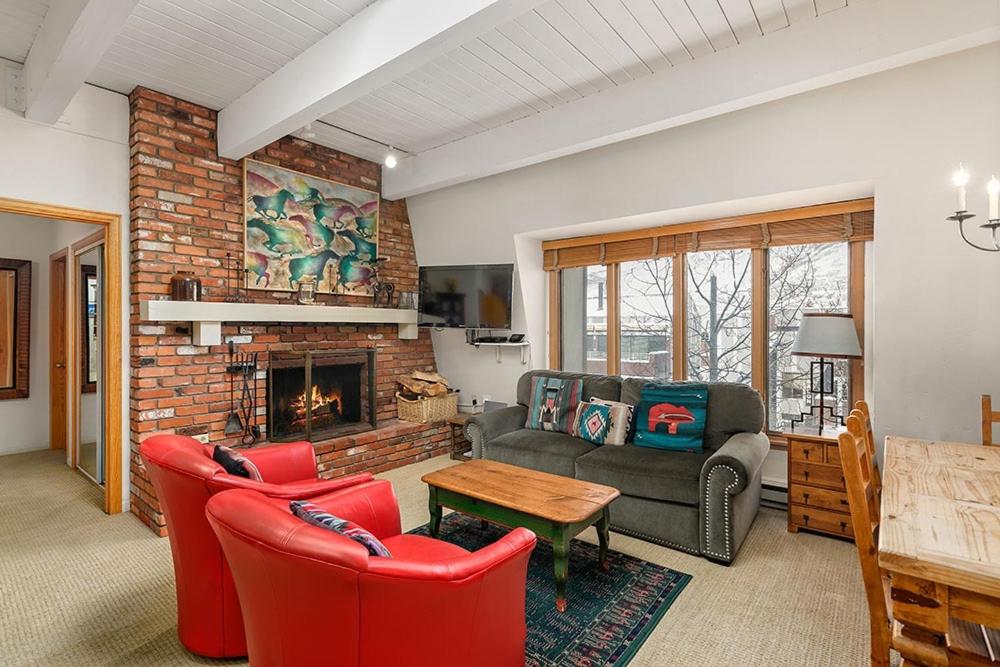 ein Wohnzimmer mit roten Stühlen und einem Kamin in der Unterkunft Chateau Chaumont Unit 19, Spacious Top-Floor Condo with Great Location in Aspen