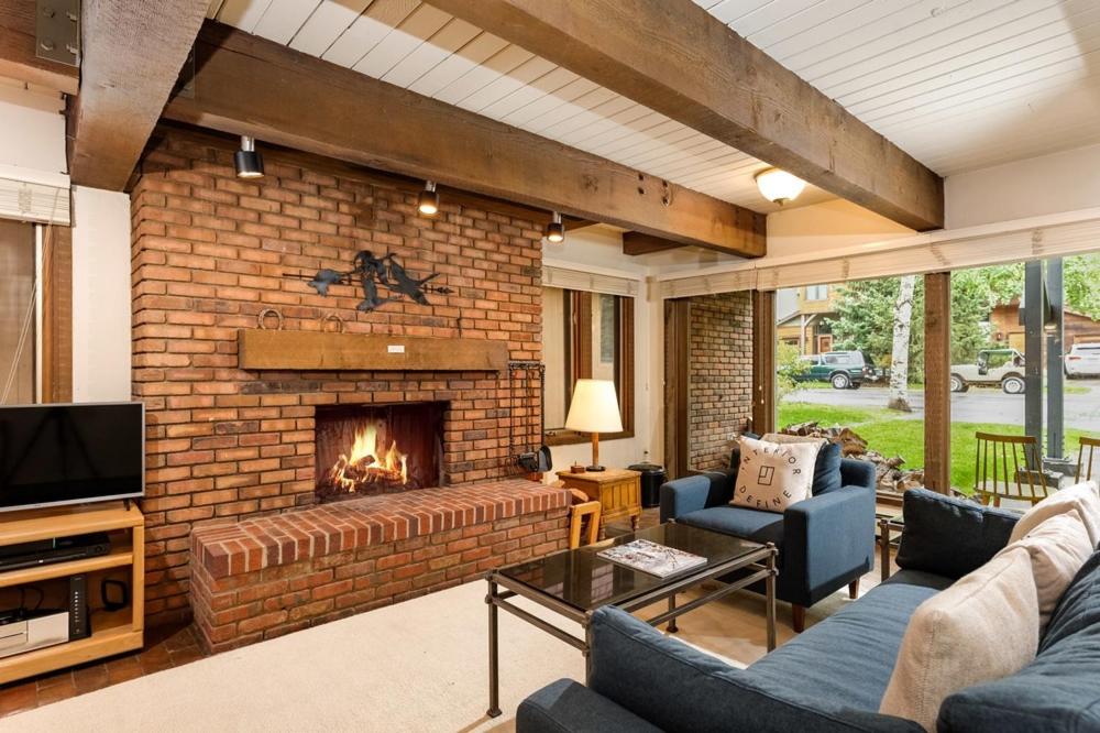sala de estar con chimenea de ladrillo y muebles en Cottonwoods Unit 1F, Stylish Condo with Excellent West End Location, Wood-Burning Fireplace, en Aspen