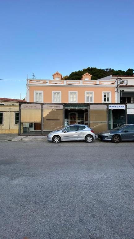 3 voitures garées dans un parking devant un bâtiment dans l'établissement Brandão House, à Caparica