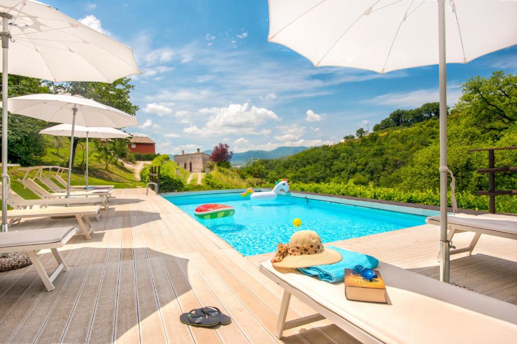 einen Pool mit Stühlen und Sonnenschirmen sowie einen Pool in der Unterkunft Borgo Canapegna - 2 private villas and 3 private pools in the heart of Le Marche in Fabriano