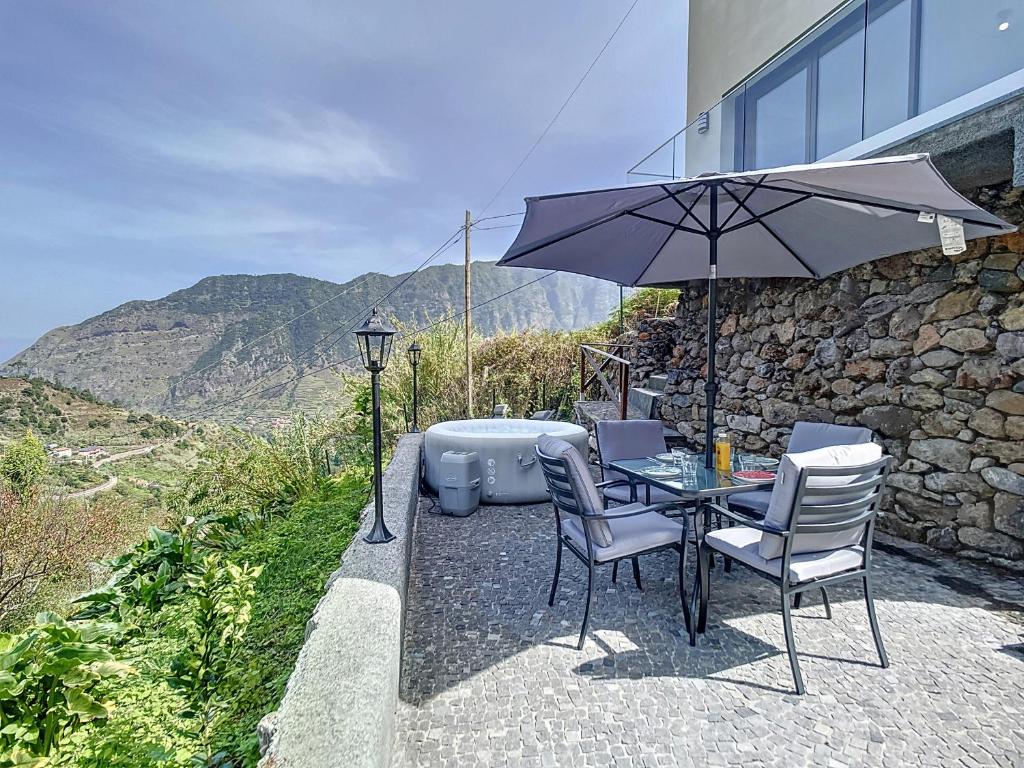 - une table et des chaises avec un parasol et une baignoire dans l'établissement Mystic Mountain by Atlantic Holiday, à São Vicente