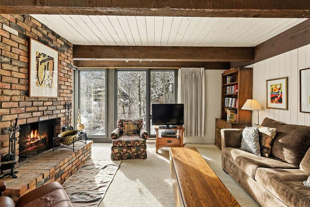 a living room with a couch and a fireplace at Chateau Roaring Fork Unit 29, Sunny, Corner Condo with River Views in Aspen