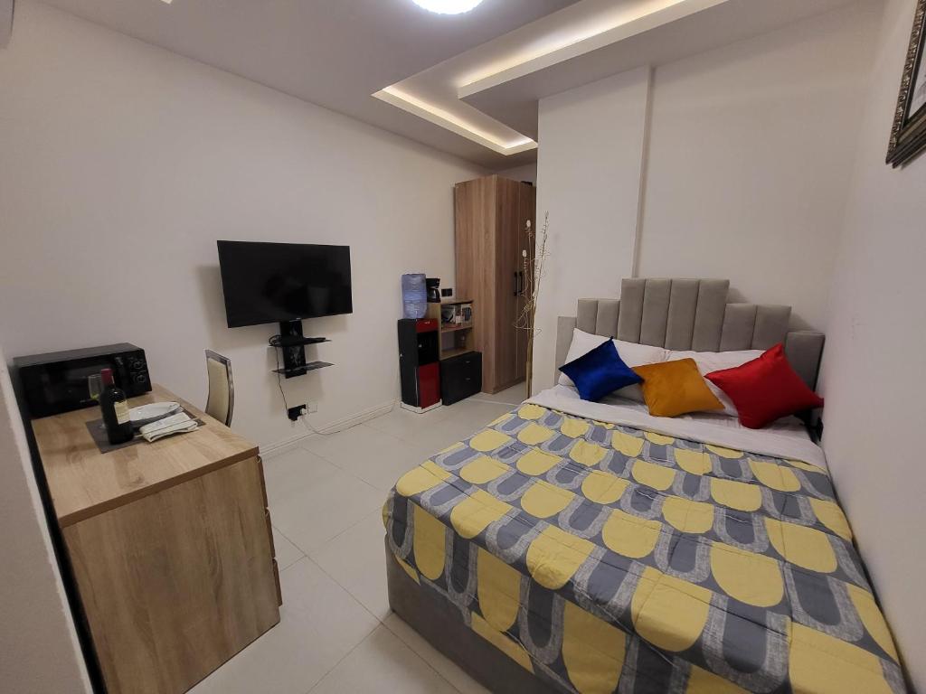 a bedroom with a bed with colorful pillows and a television at Ikoyi/Banana Studio Room in Lagos