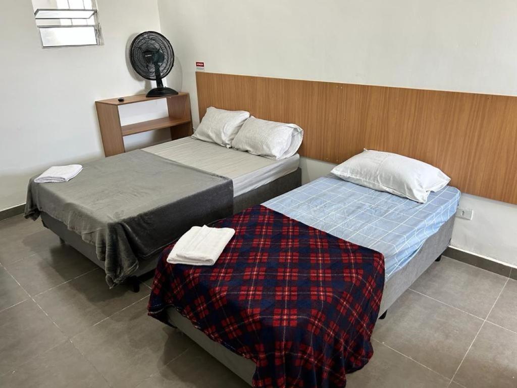 a room with two beds and a fan at Studio mobiliado na Vila Guilherme - São Paulo/SP in São Paulo