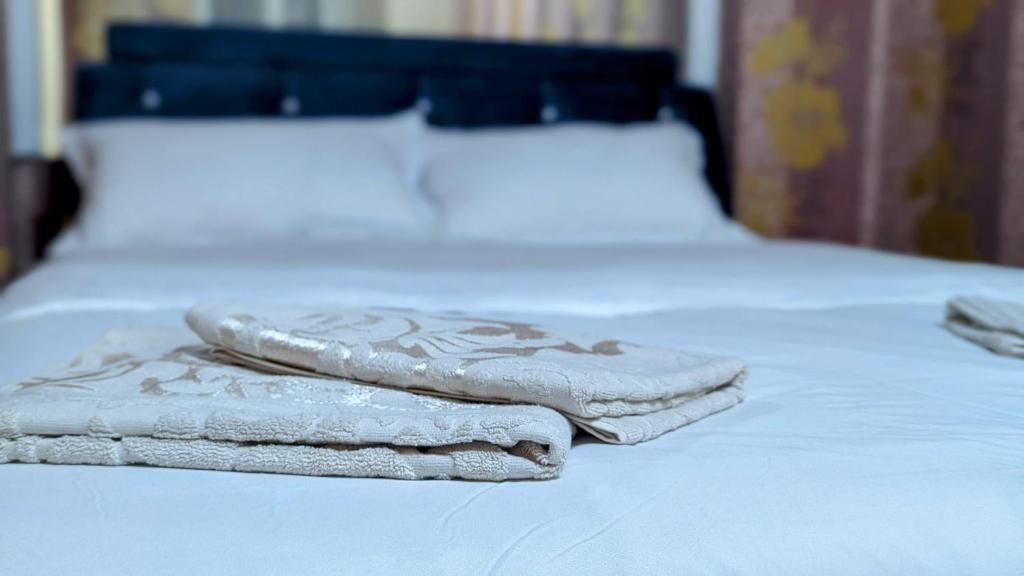 twee handdoeken zitten bovenop een bed bij Apartments in the center in Taraz