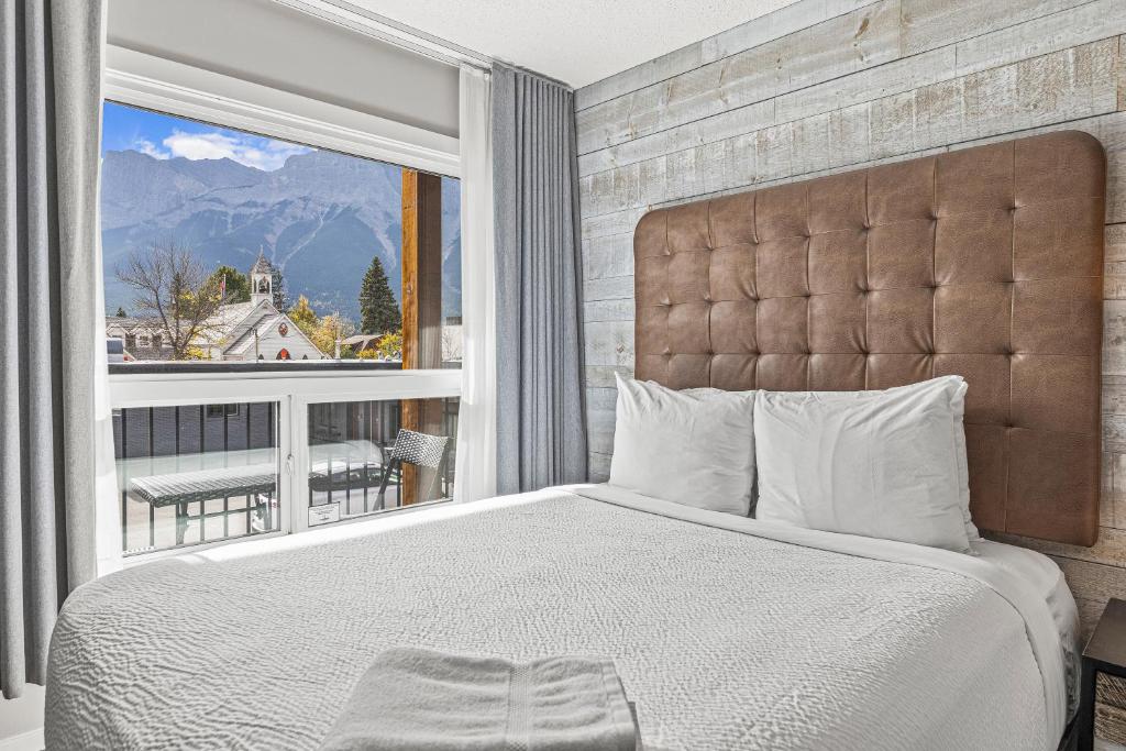 a bedroom with a large bed and a large window at Lamphouse By Basecamp in Canmore