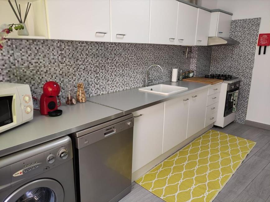 a kitchen with white cabinets and a sink and a dishwasher at A Casa da Nocas- Quarto Yellow in Setúbal