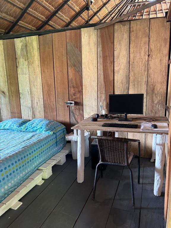 een bureau met een computer en een bed in een kamer bij Eco Hostal Villa Canada - A Sustainable Oasis on Isla de Tierra Bomba in Playa Punta Arena