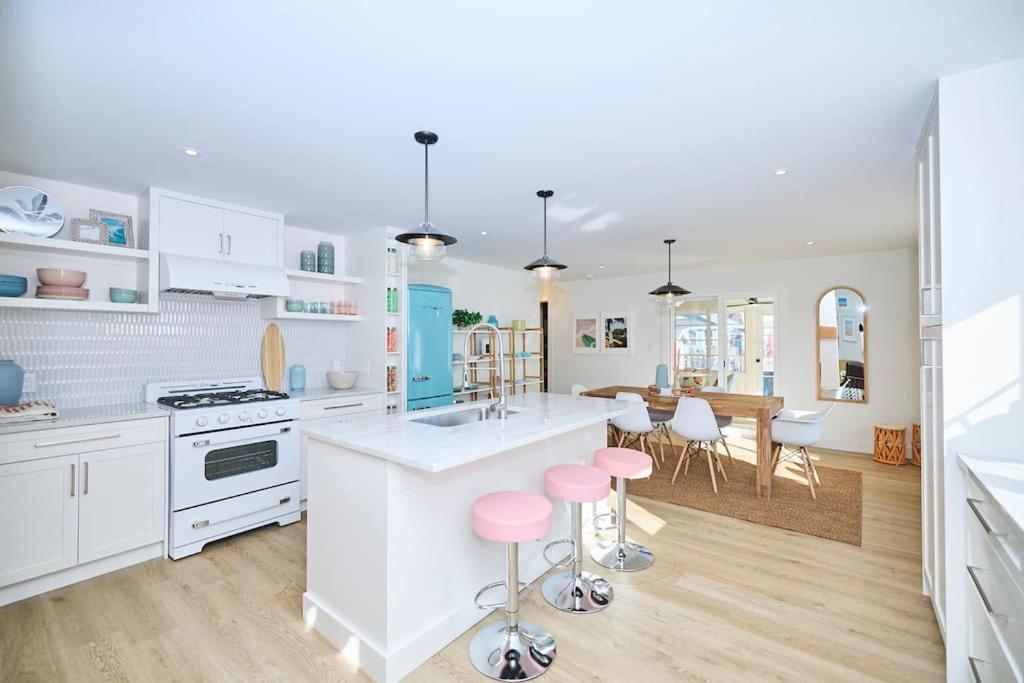 una cocina con armarios blancos y taburetes rosados en Beachside Abode Crystal Beach en Fort Erie