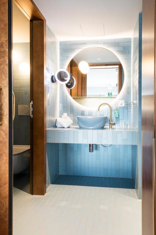 uma casa de banho azul com um lavatório e um espelho em Hotel Aare Thun em Thun