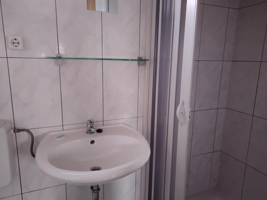 a white bathroom with a sink and a shower at FEWO Isla 2 in Elmenhorst