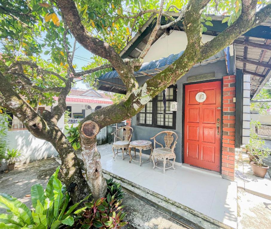 una puerta roja en una casa con un árbol en Dusun Indah Cottage 1, en Bayan Lepas