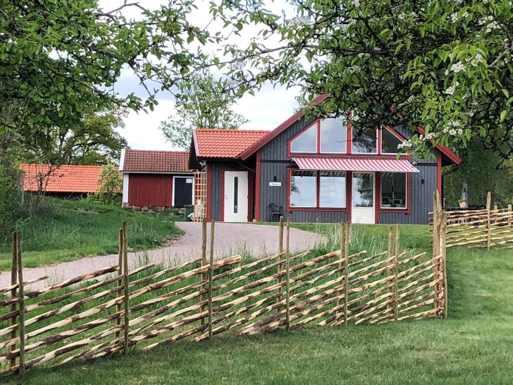 a red and black house with a wooden fence at Joarsbo, Stuga 3, Klinten in Kalv