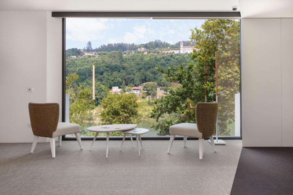 Zimmer mit 2 Stühlen, einem Tisch und einem großen Fenster in der Unterkunft Douro Green in Castelo de Paiva