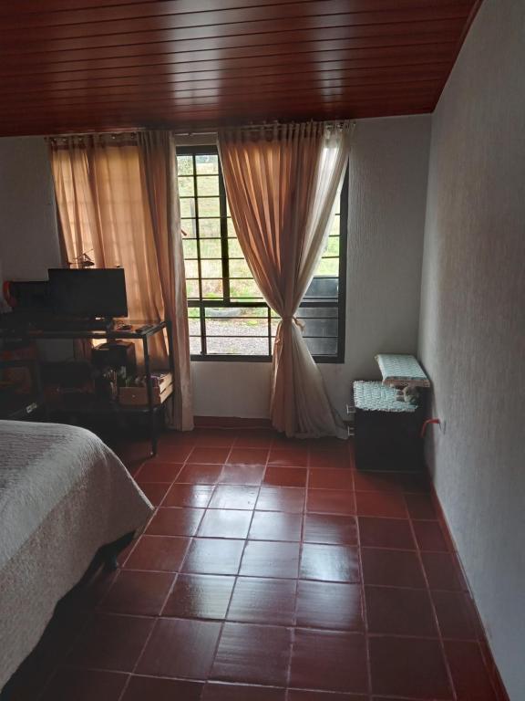 a bedroom with a bed and a window and a tiled floor at Casa Campo La Milagrosa in Cómbita