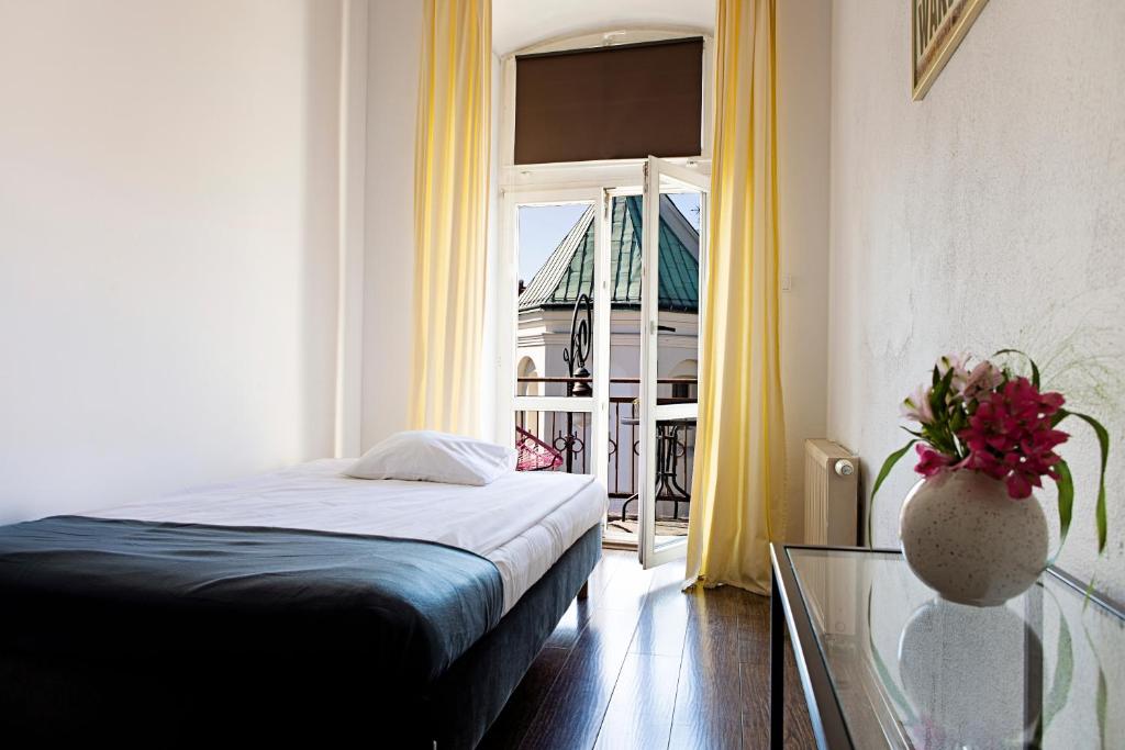 盧布林的住宿－皇族旅館，一间卧室设有一张床、一张玻璃桌和一扇窗户
