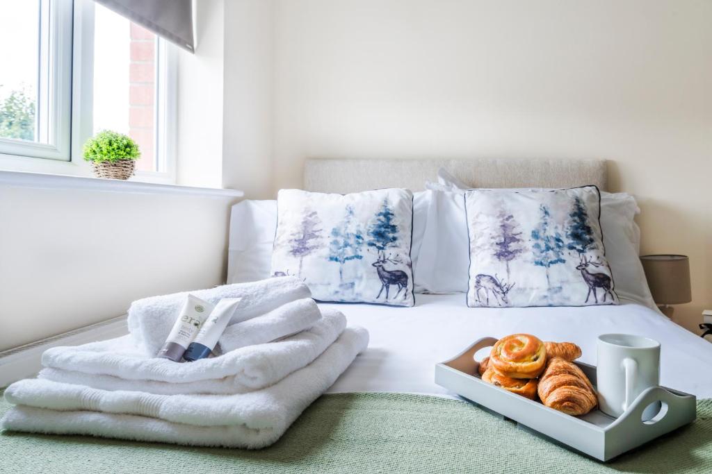 a bed with towels and a tray of pastries on it at Beautiful Gloster House with a Large Garden & Free Parking in Woking