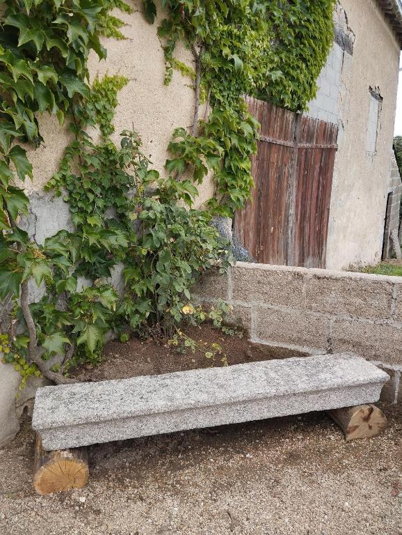 a stone bench sitting in front of a building at Maison au calme avec vue étang in Clessé