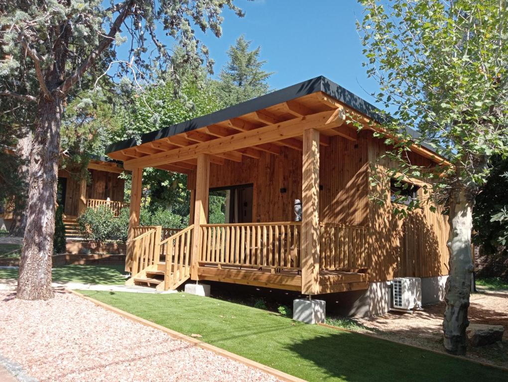 eine große Holzhütte mit einer großen Terrasse in der Unterkunft Jardín Las Secuoyas in Becerril de la Sierra