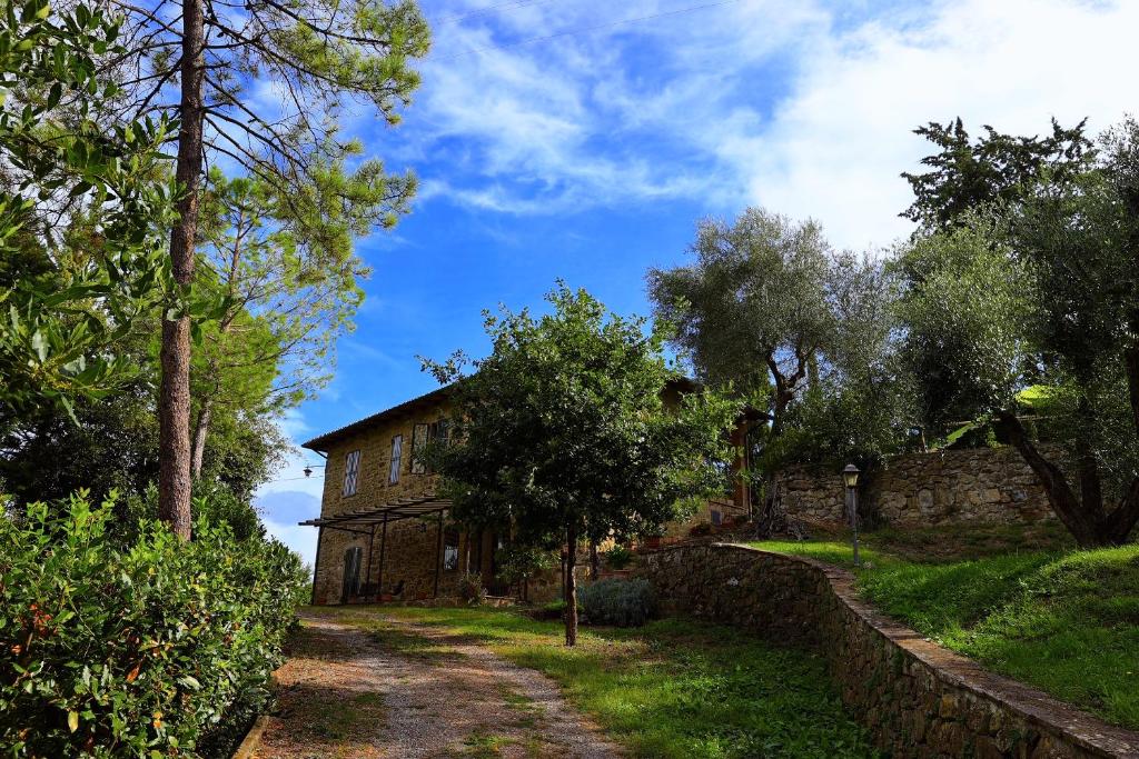 an old stone house with a stone wall and trees at Agriturismo Podere Cottimellino - B&B in Val d'Orcia in Montalcino