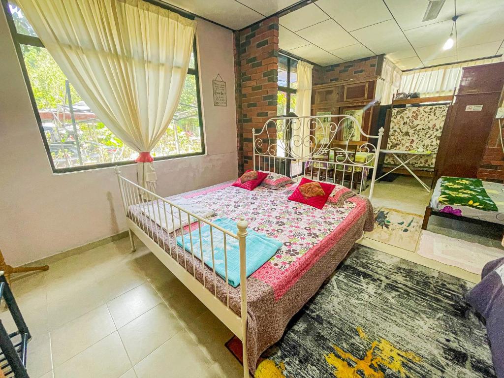 1 dormitorio con cama de metal y almohadas rojas en Dusun Indah Cottage 2 en Bayan Lepas