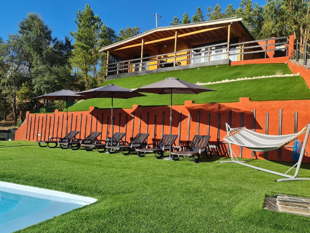 eine Gruppe von Stühlen und Sonnenschirmen neben einem Pool in der Unterkunft Villa dos Pensamentos in Vila de Rei