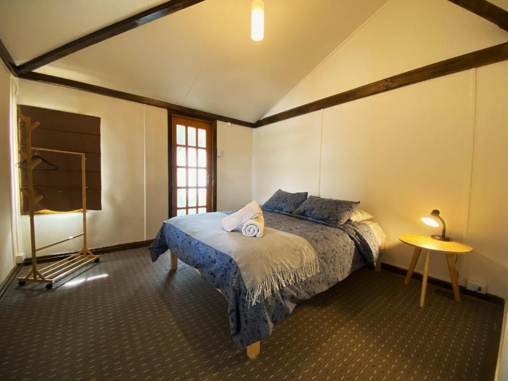1 dormitorio con cama, mesa y ventana en Kawi Hostel, en Puerto Natales