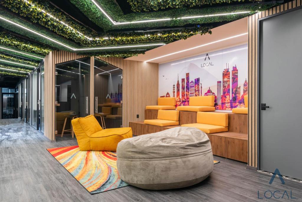 A colorful shared lounge with sofas, an armchair, a large ottoman, and a city mural.