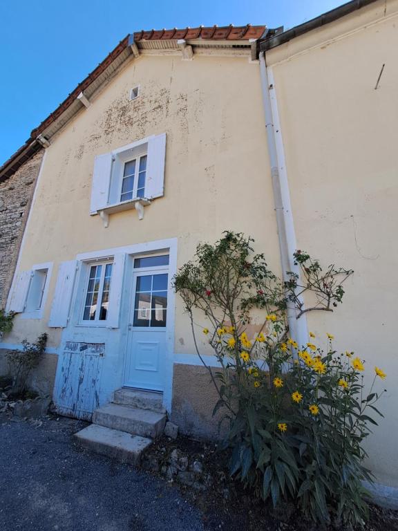 una casa con una puerta azul y algunas flores en Le val d Arlette, en Arsonval