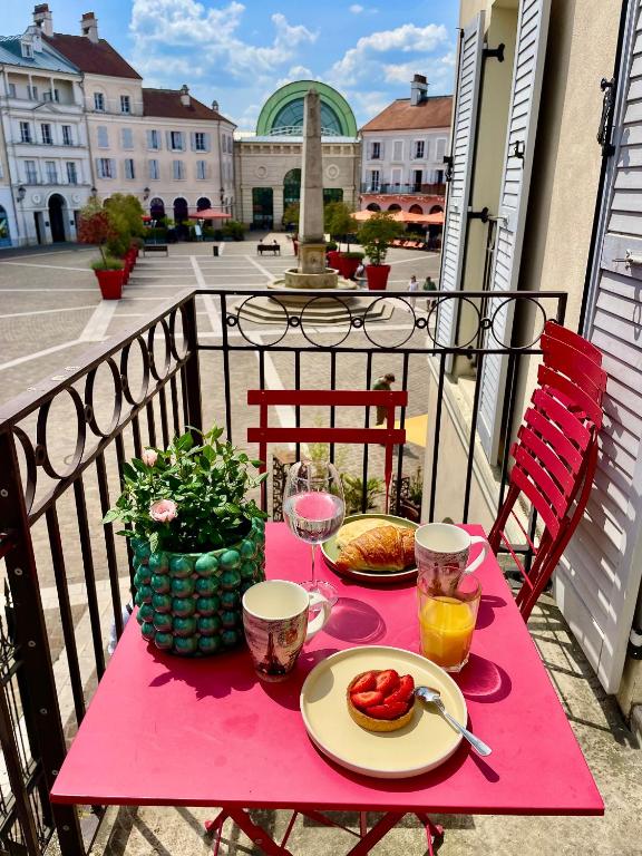une table rose avec des assiettes de nourriture sur un balcon dans l'établissement Appt Vue Place de Toscane - 4min Disneyland-PARIS, à Serris