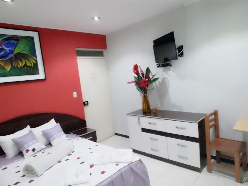 een slaapkamer met een bed en een rode muur bij Hotel Botón de Oro in Puerto Maldonado