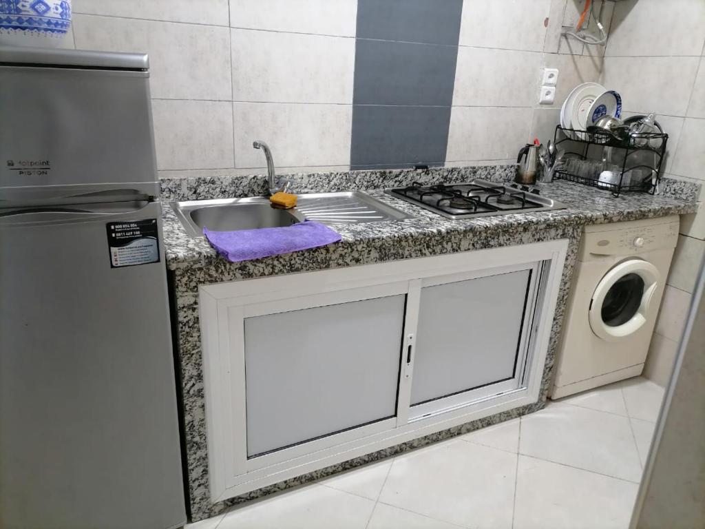 een keuken met een wastafel en een wasmachine bij Appart happiness family only in Tanger