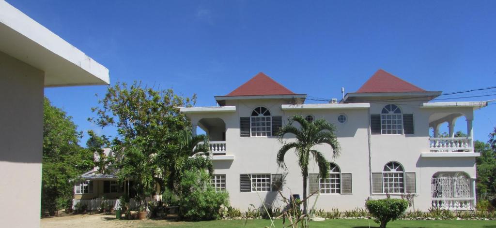 een groot wit huis met een rood dak bij Nelsons Retreat in Negril
