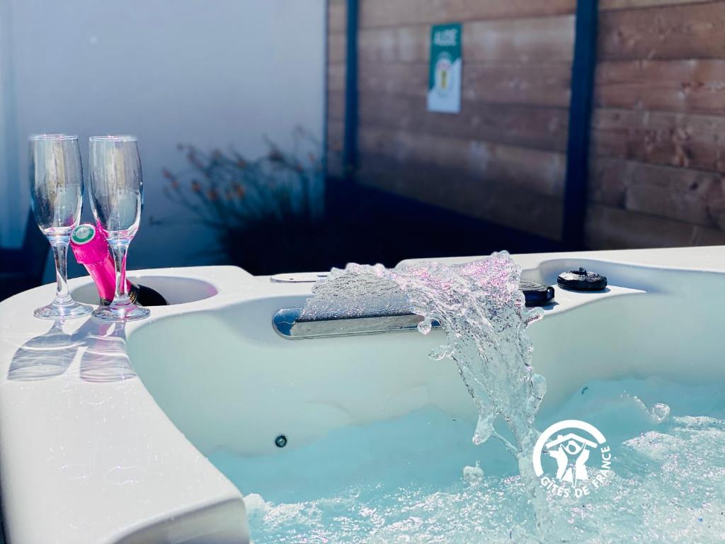 a bath tub with two wine glasses on a table at Gîte & Spa 4 étoiles - Le Villemachois - Neuf - Tout confort in Villemoustaussou