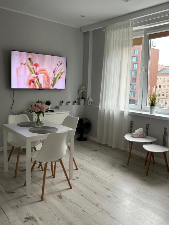 ein Wohnzimmer mit einem Tisch und Stühlen sowie einem TV in der Unterkunft Apartament na Dworcowej Centrum in Breslau