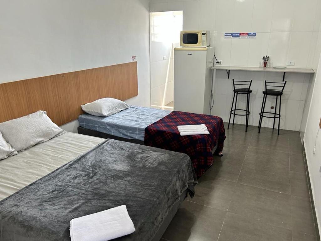um quarto com duas camas e uma cozinha com um balcão em Studio 23m² Zona Norte/SP ao lado Expo Center Norte em São Paulo