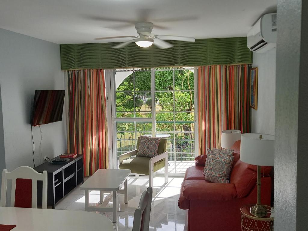 a living room with a red couch and a window at Marchabell by the Sea E22 in Ocho Rios