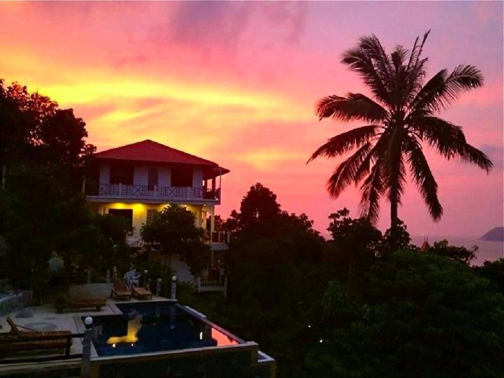 a house with a palm tree in front of a sunset at Viking House Villa Deluxe in Ko Tao